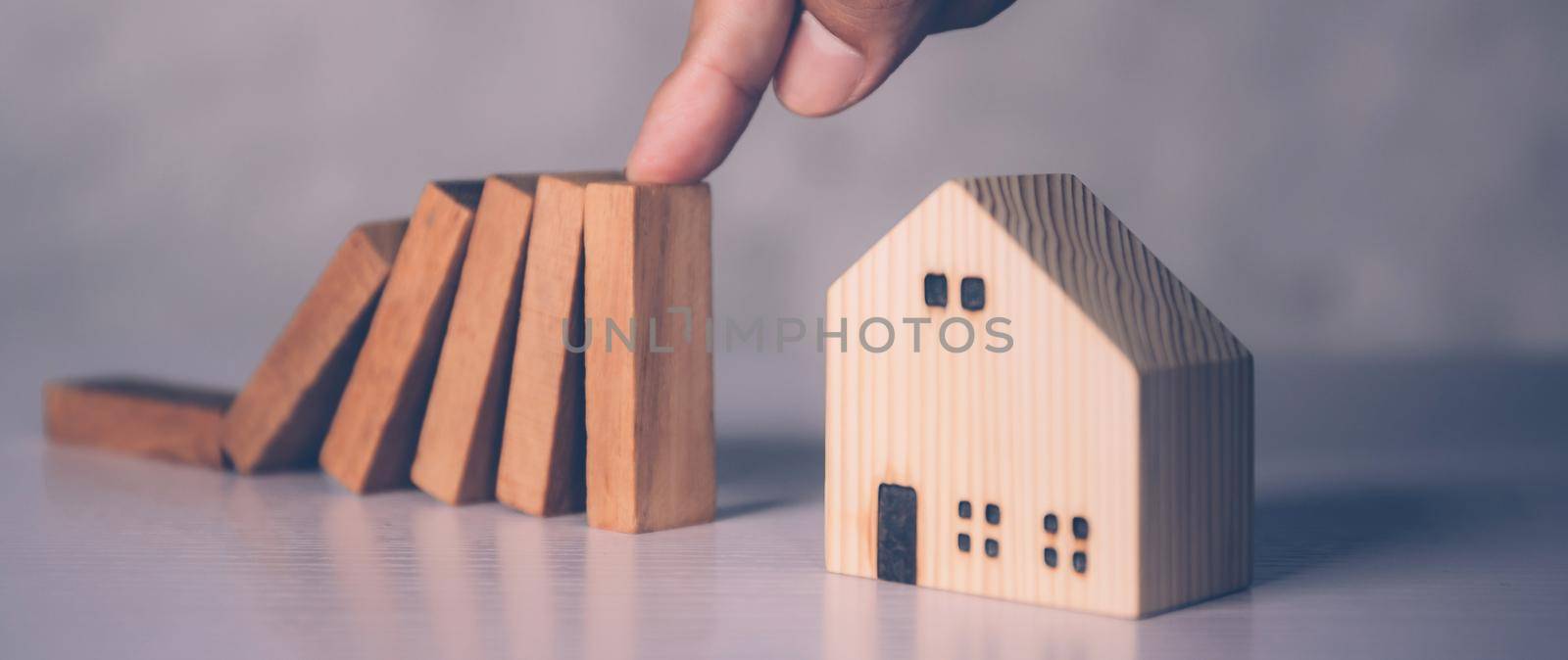 Hands of businessman stop risk about home with block wooden and safety, investment and insurance about real estate and property, planning and strategy, loan and debt of house, business concept.