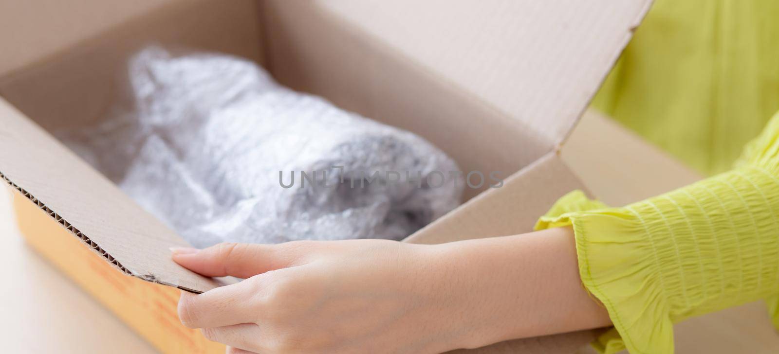 Closeup hand of woman opening parcel box with check product at home, female unpack with knife, delivery and shipping, shipment and express for shop, online shopping store and service concept.