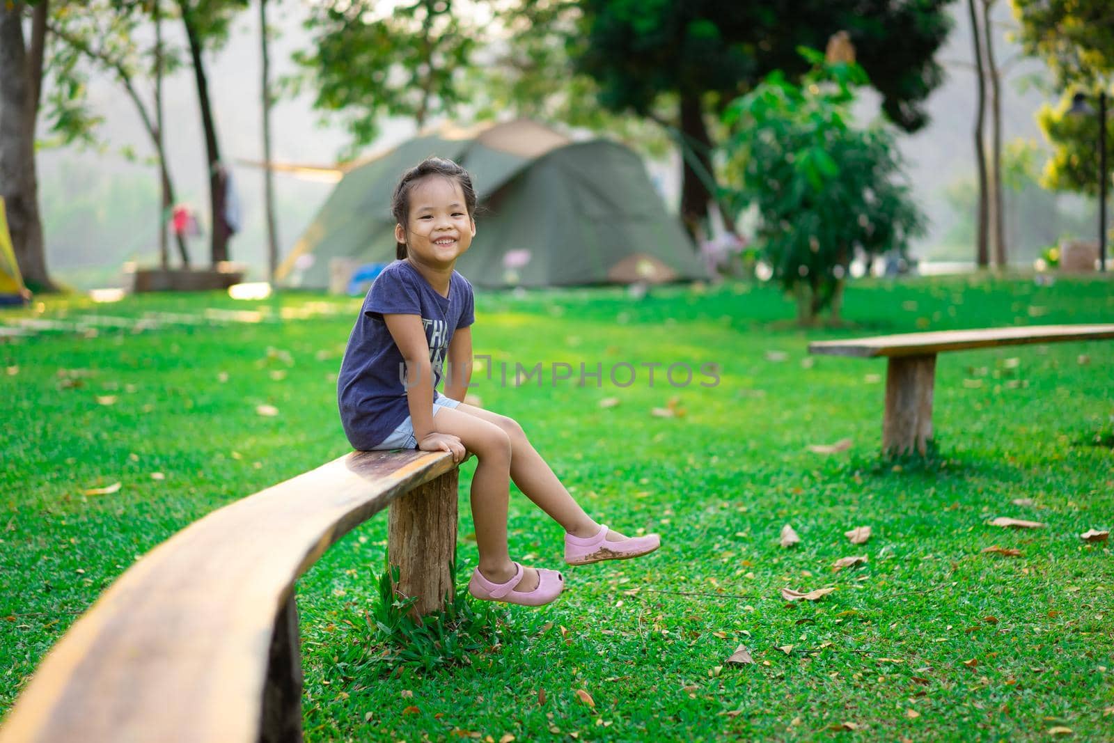 little girl sitting on bench while going camping