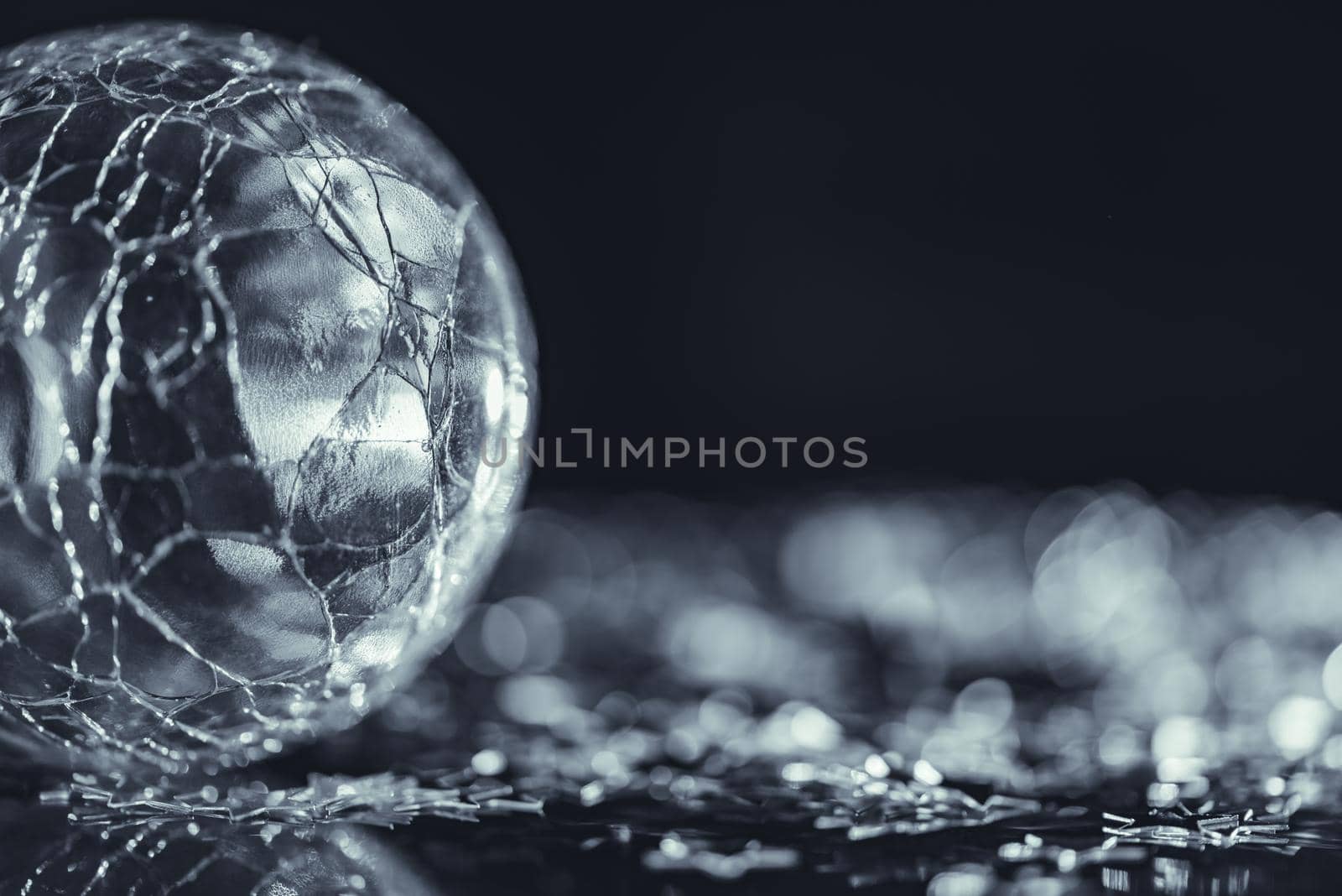 Macro photo of cracked glass sphere, bright silver star with light bokeh