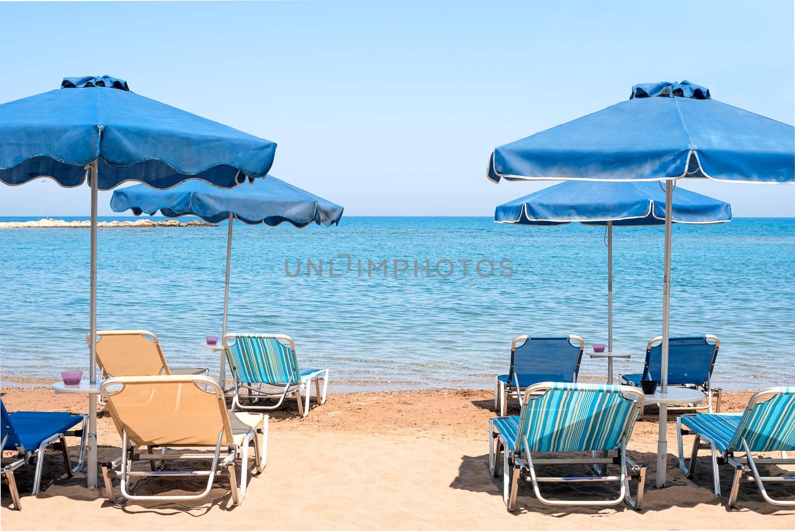 View of the transparent blue sea from coast with bright blue umbrellas