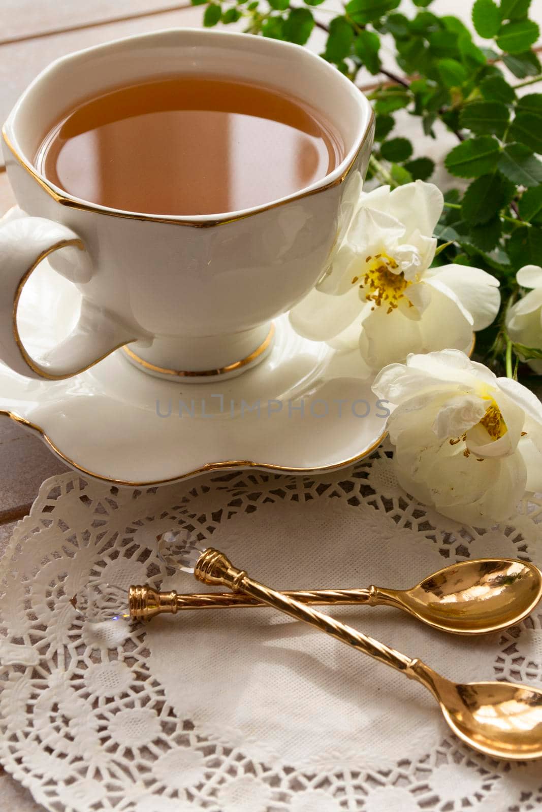 cup of tea with little roses on white wooden table. Vertical image