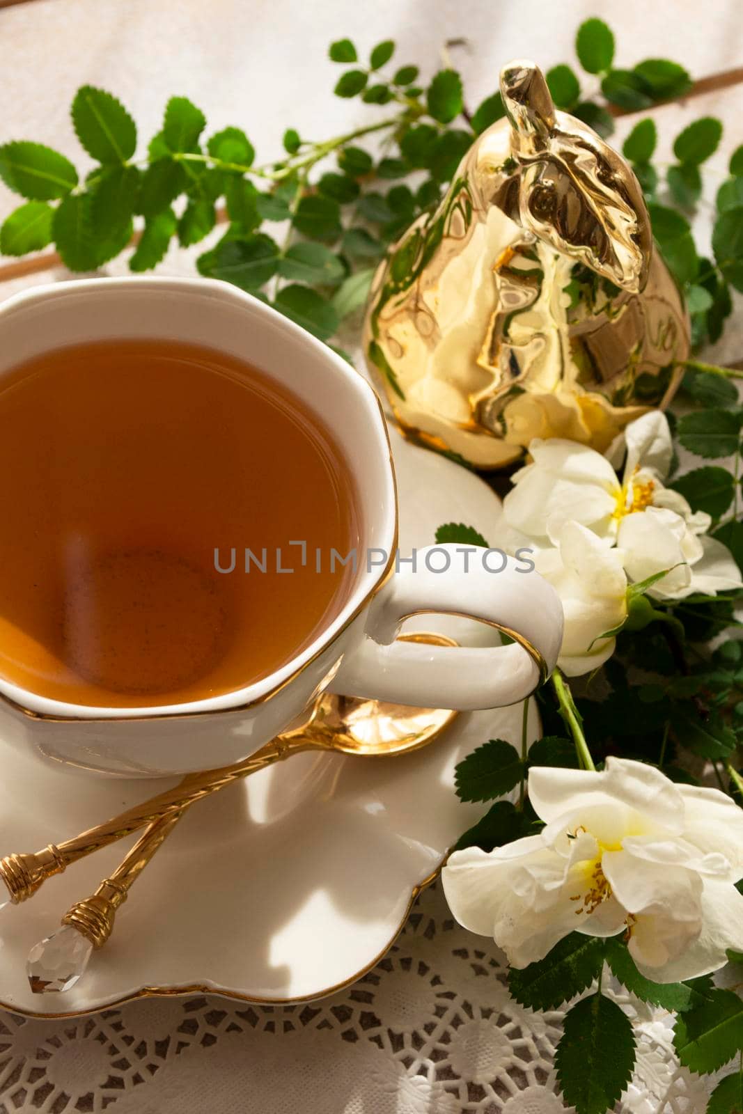 tea roses in a white cup on a wooden table. rustic style. Vertical image