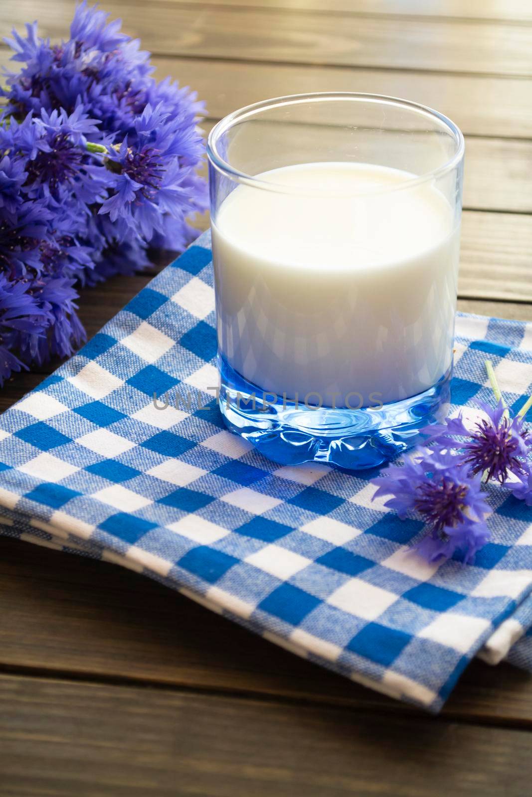 Jar of milk and cornflowers on a old brown wooden table. Vertical image