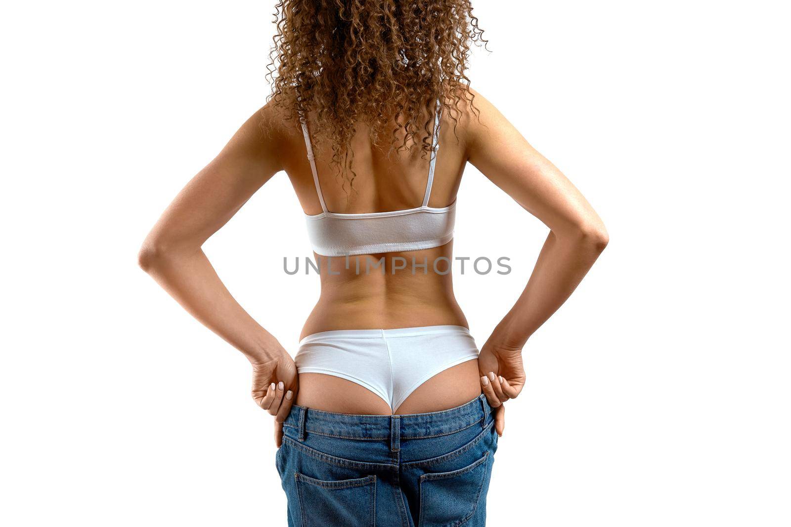 Young woman in jeans. Sexy girl stands with her back to the camera