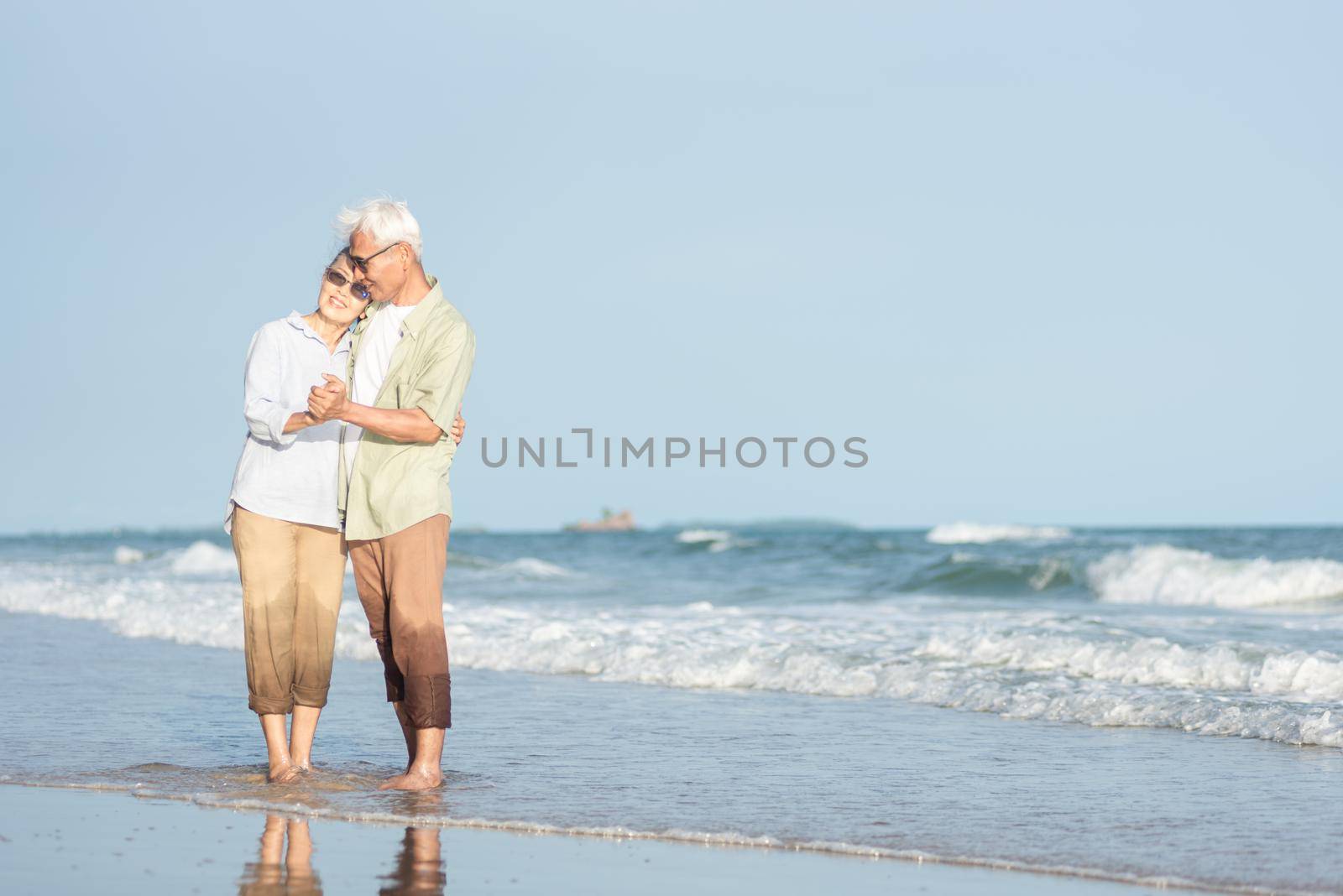 Happy Asian senior man and woman couple smile dancing resting relax on the beach by Sorapop