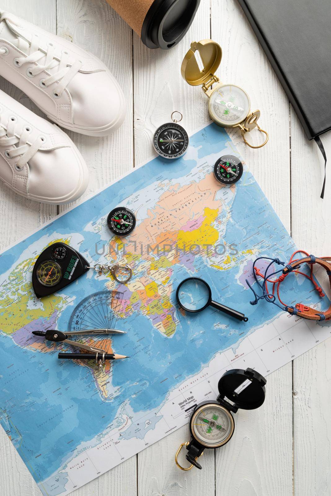 Flat lay travel. Top view map of the world with various compasses, shoes, magnifying glass. Planning a trip