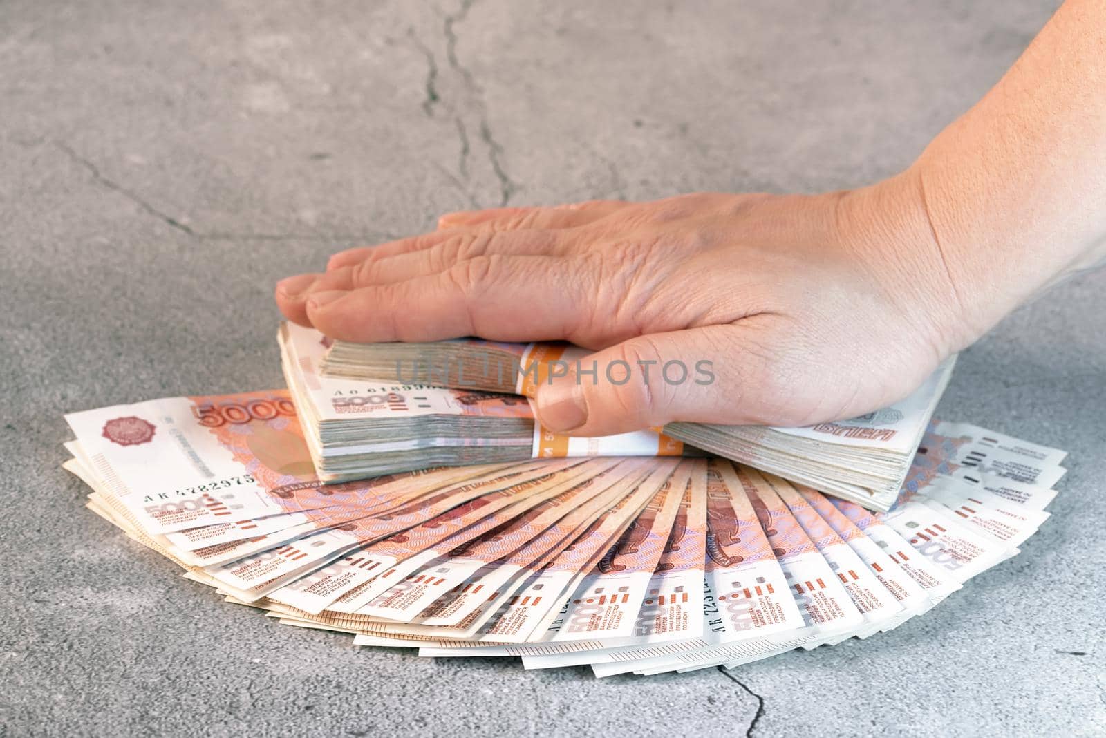 Heap of red 5000 russian rubles banknotes with the hand on top