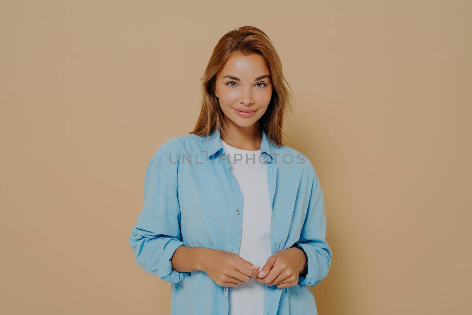 Young woman in stylish outfit posing on beige background by vkstock