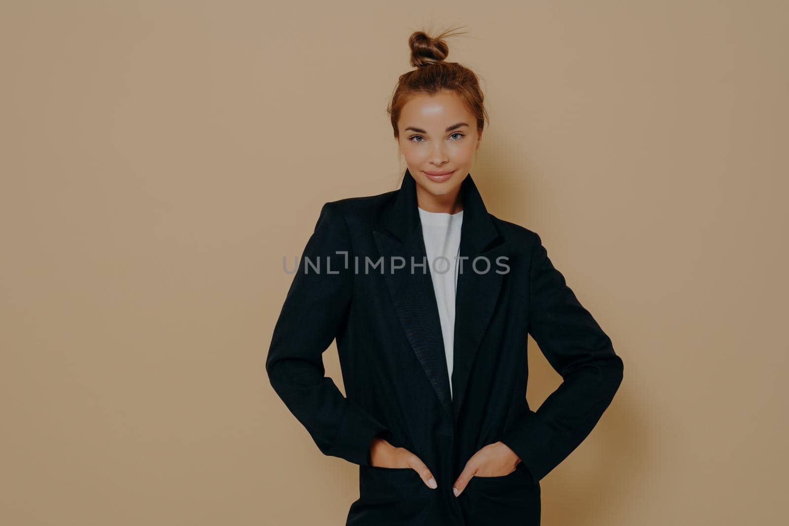 Attractive young model female in black suit with hair tied up in high bun by vkstock