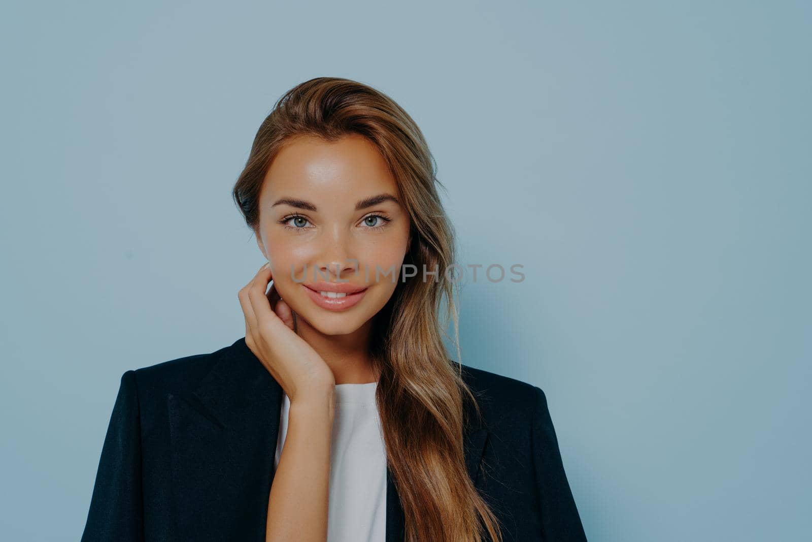 Attractive woman with gentle smile against light blue background by vkstock