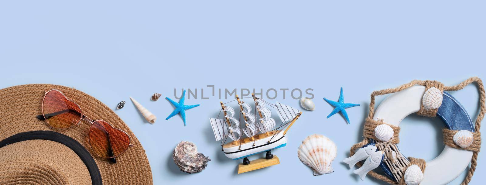 Summer beach background design concept. Top view of holiday travel with shells, hat and sunglasses on blue background.