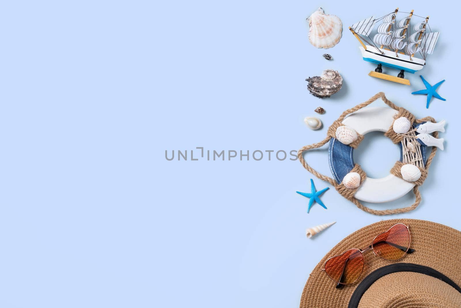 Summer beach background design concept. Top view of holiday travel with shells, hat and sunglasses on blue background.