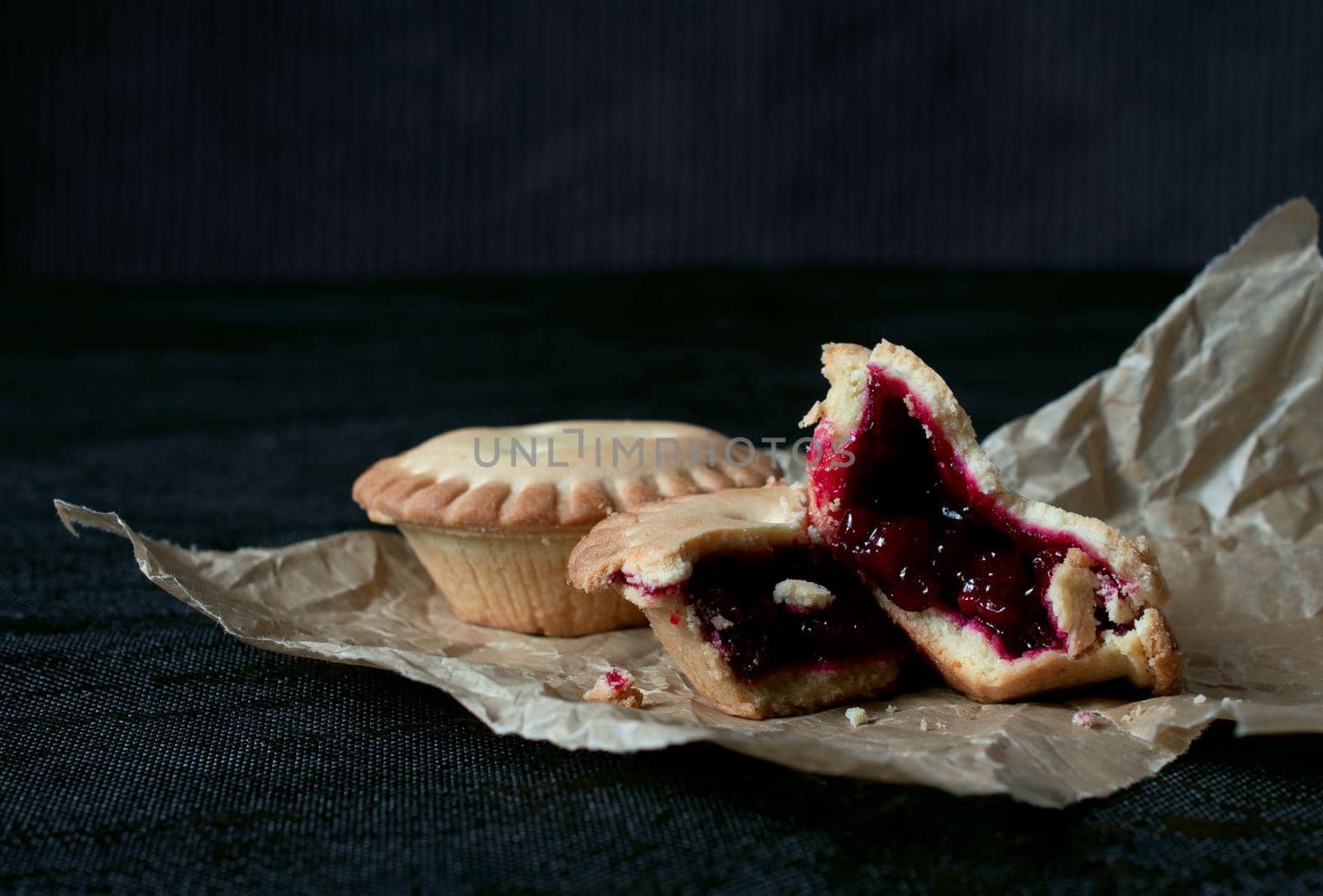 Cookies with jam on brown paper on black backgroung