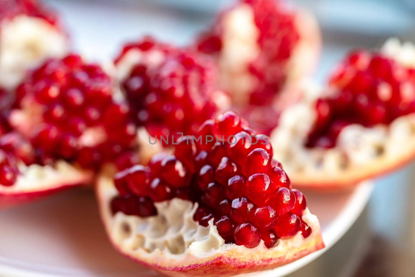 The fresh red tasty opened pomegranate on a white dish closeup