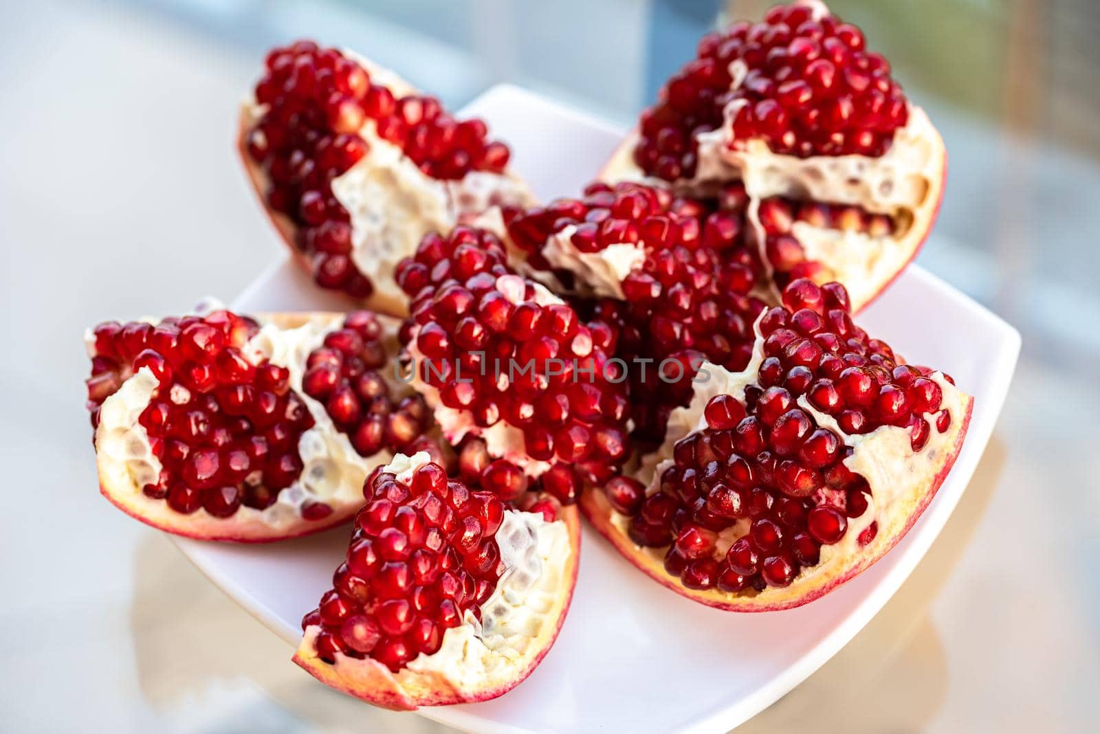 The fresh red tasty opened pomegranate on a white dish by Estival