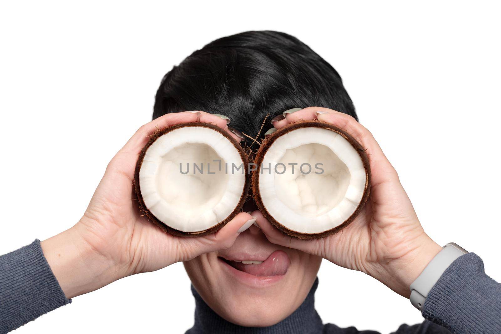 Young woman holding two half of coconut in front of eyes isolated on white background