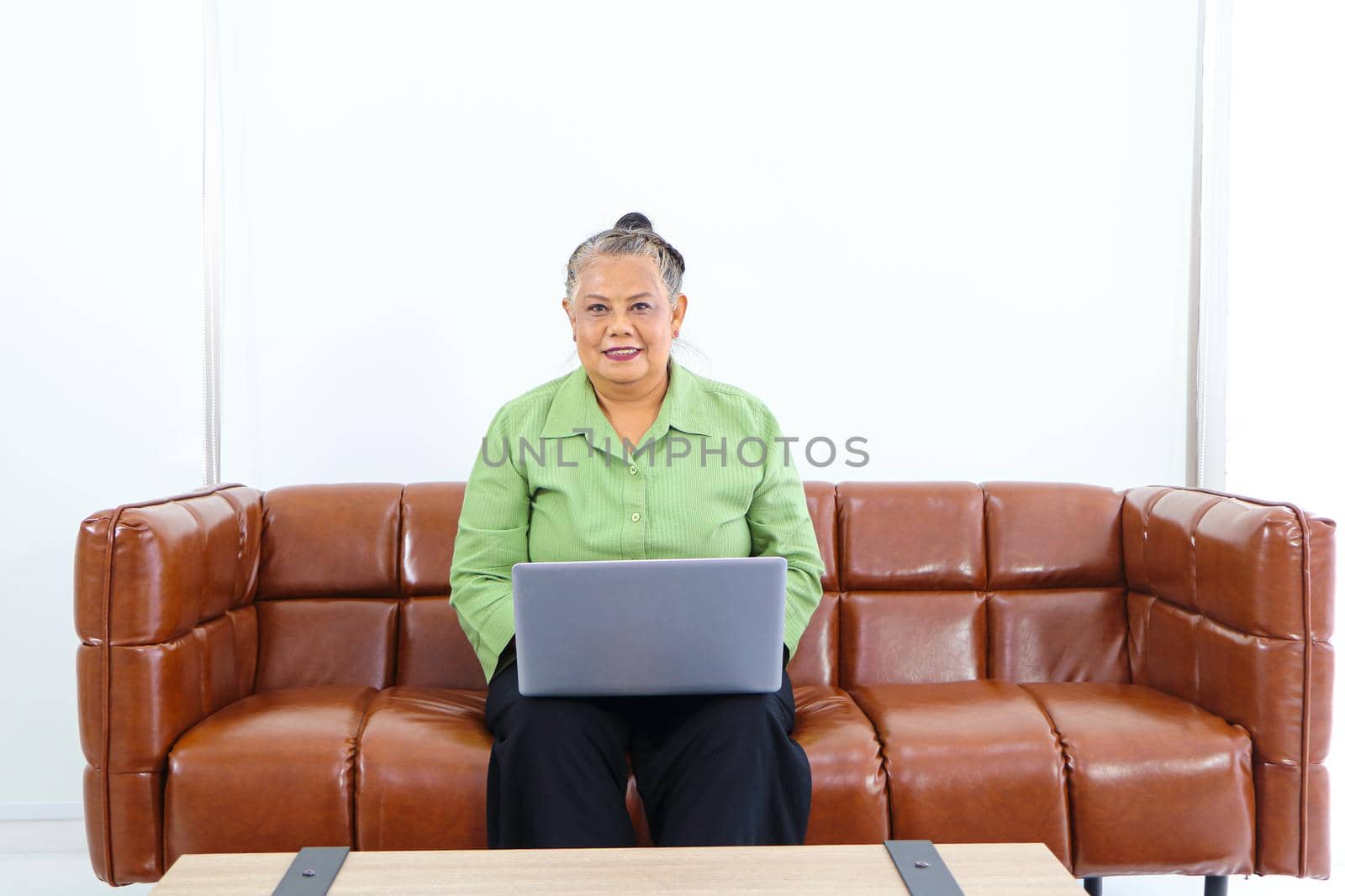 Asian women Retirement Use a smartphone and laptop in the living room concept to work at home. Quarantine to prevent spreading disease Or a conversation with someone far away Via the Internet