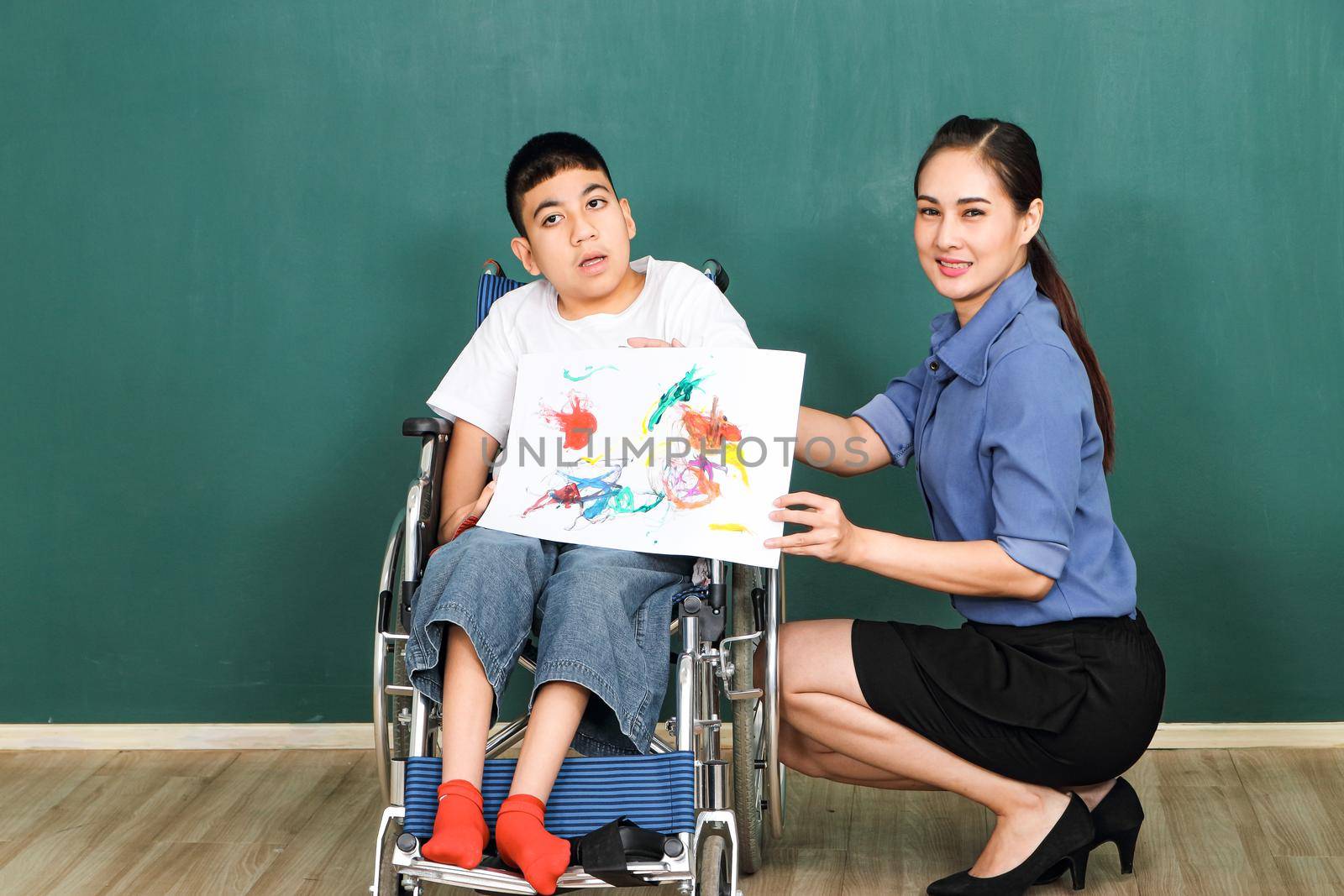 A group of young girls with disabilities and autism is training their hand and finger muscles by drawing and painting with water. With the help of teachers Happy and focused in the classroom