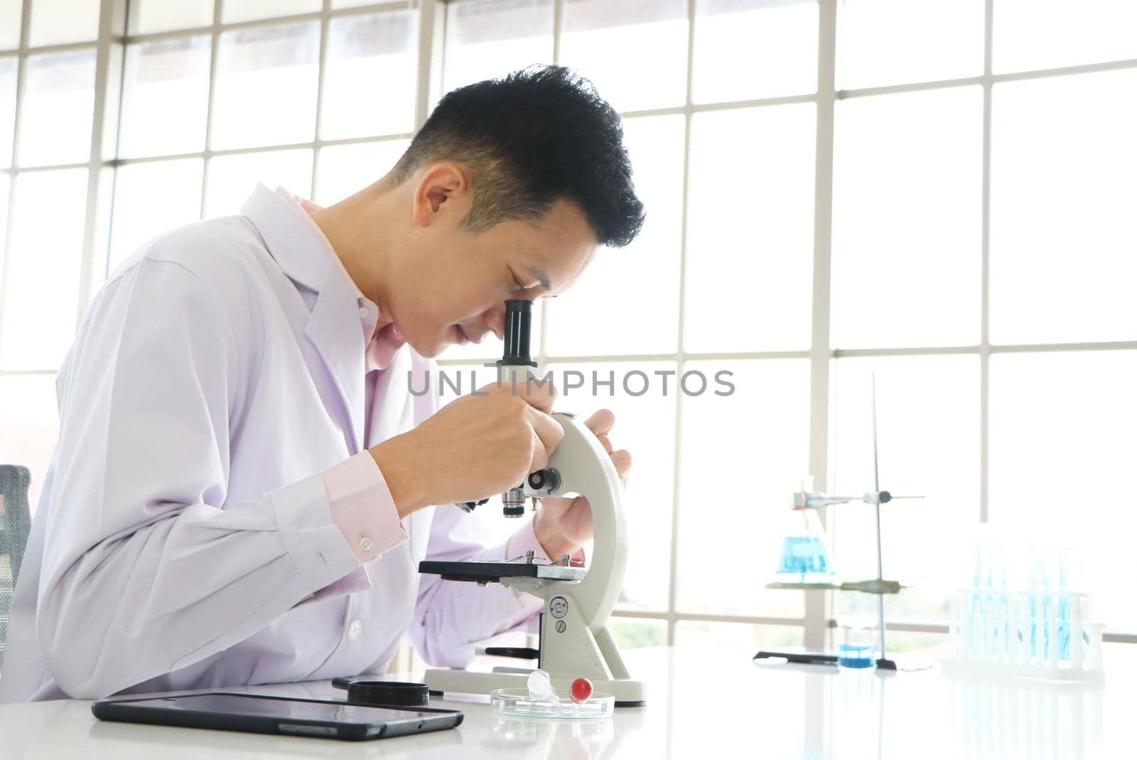 Asian scientists or chemists use a microscope. In science experiment Medical pharmaceutical research concept DNA structure, innovation and technology