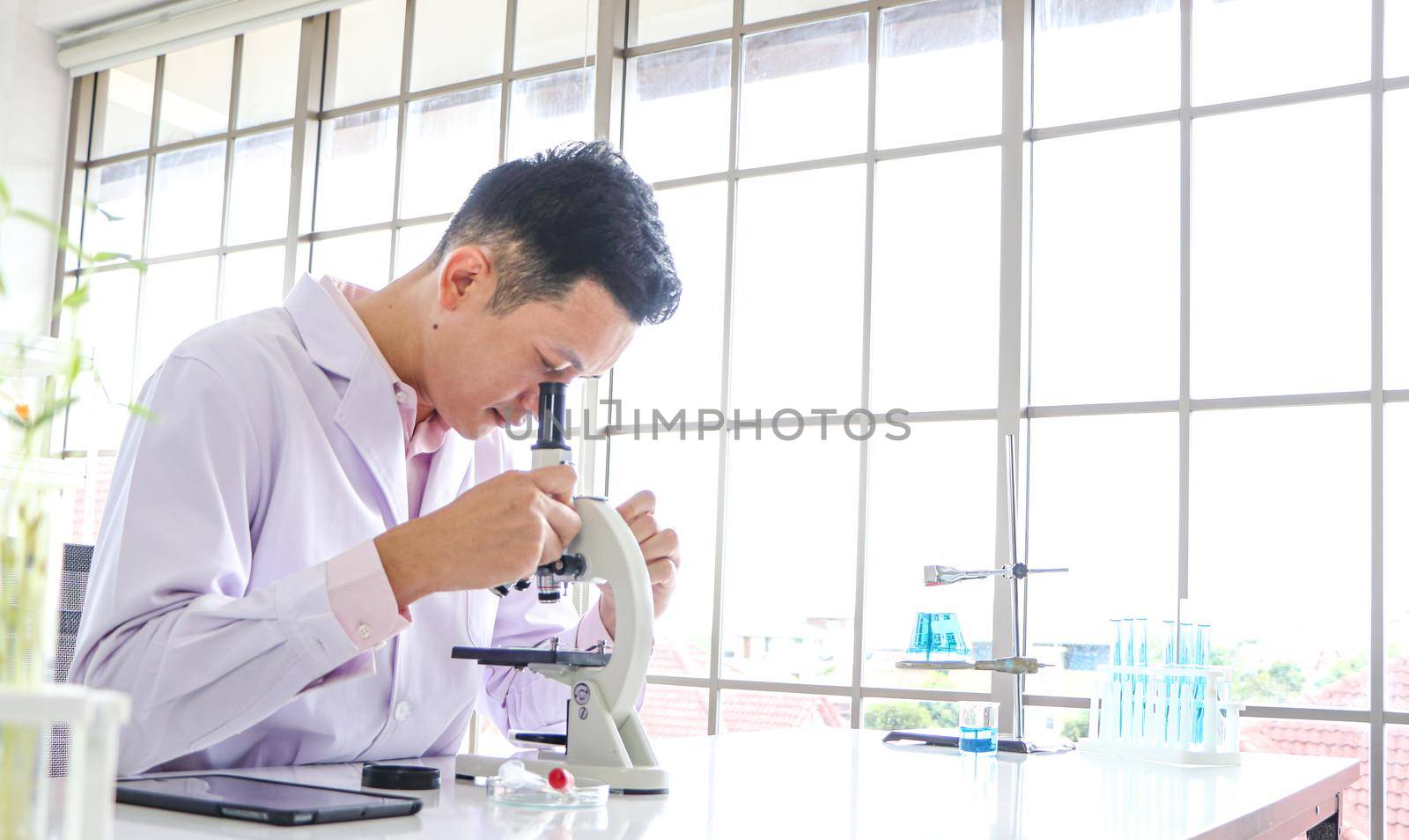 Asian scientists or chemists use a microscope. In science experiment Medical pharmaceutical research concept DNA structure, innovation and technology