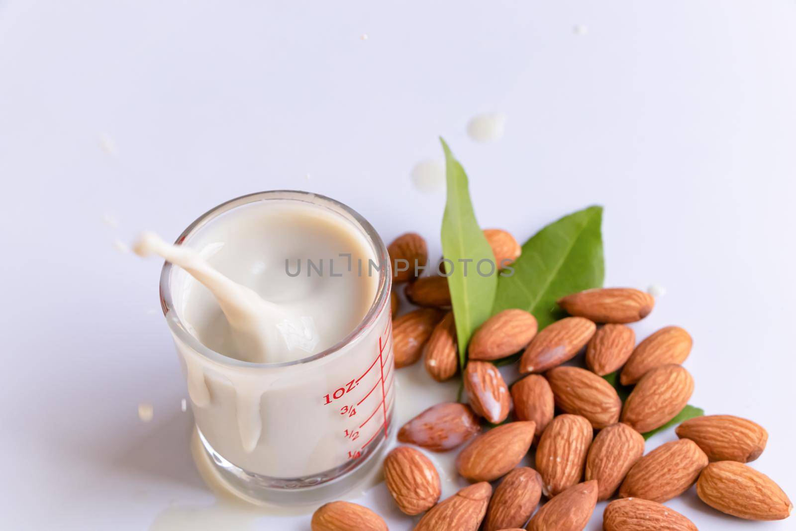 Almond milk in glass with almonds on wooden table by atitaph