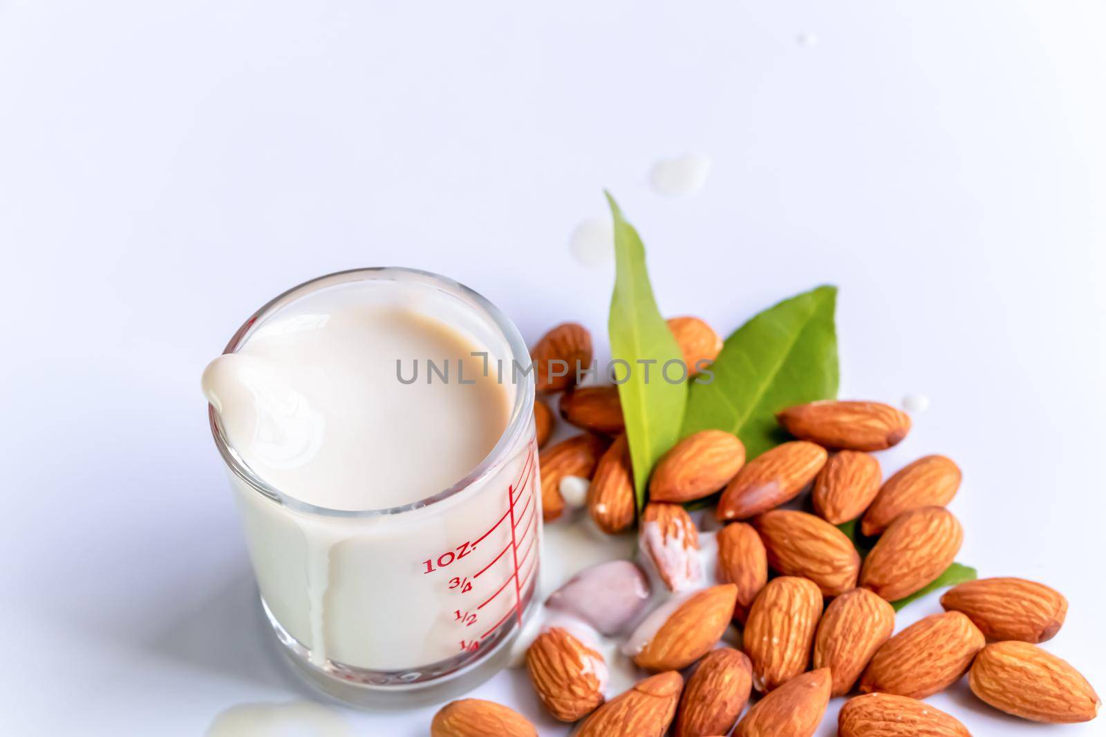 Almond milk in glass with almonds on wooden table by atitaph