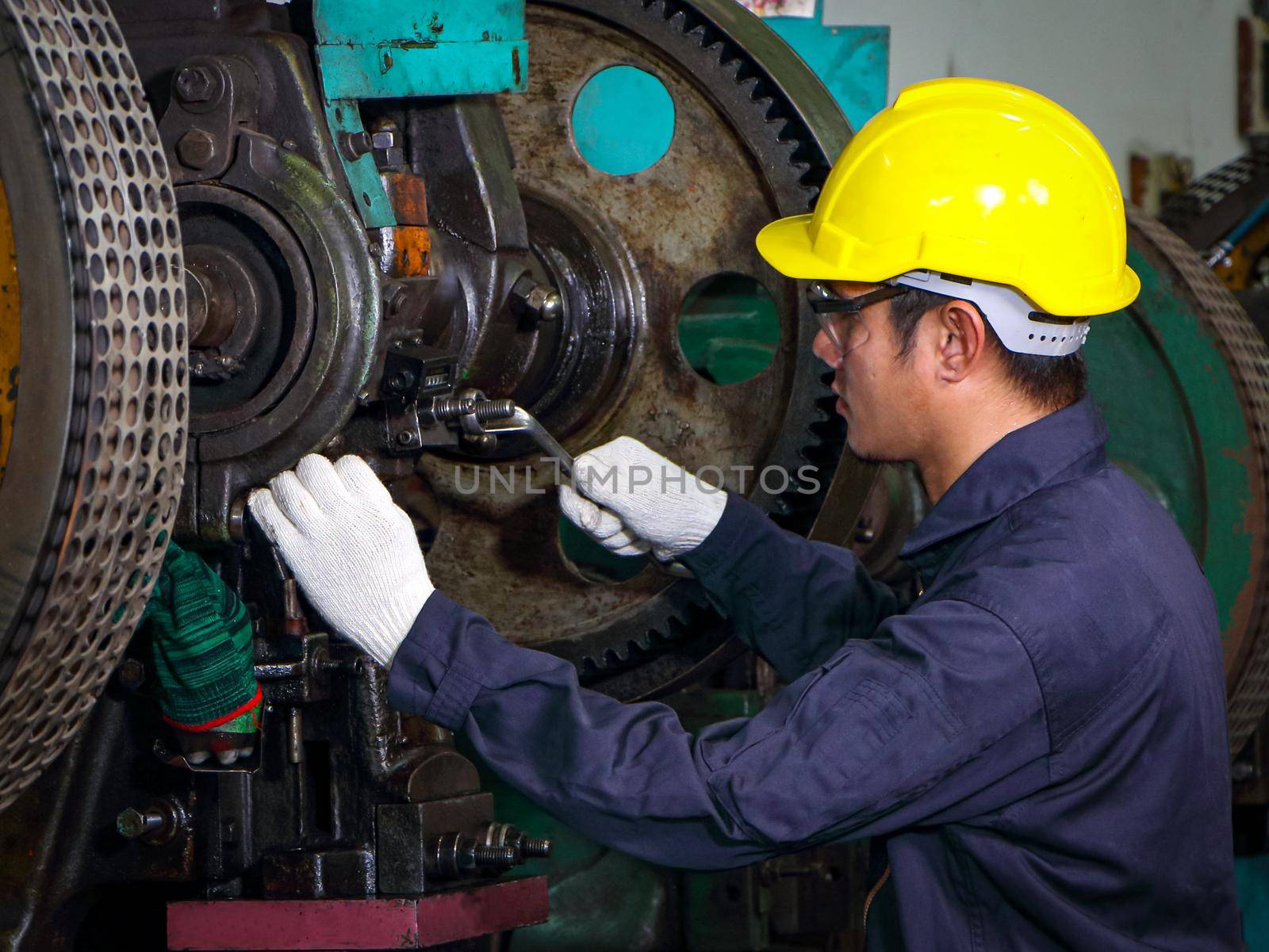 Asian technician Wear uniform Helmet with wrench In machine inspection, the concept of machine control, maintenance and check the operation of machines Working in industrial and manufacturing plants