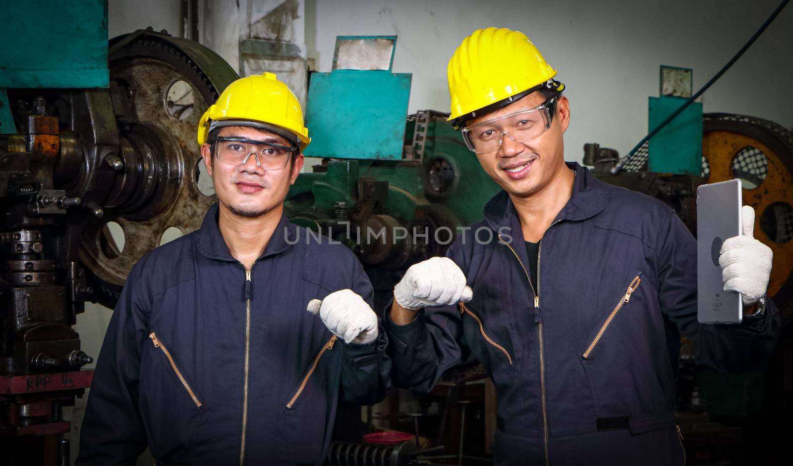 Two Asian male workers in a Yunifom uniform. Wear a safety hat and wear gloves. Greeting by bumping hands by atitaph