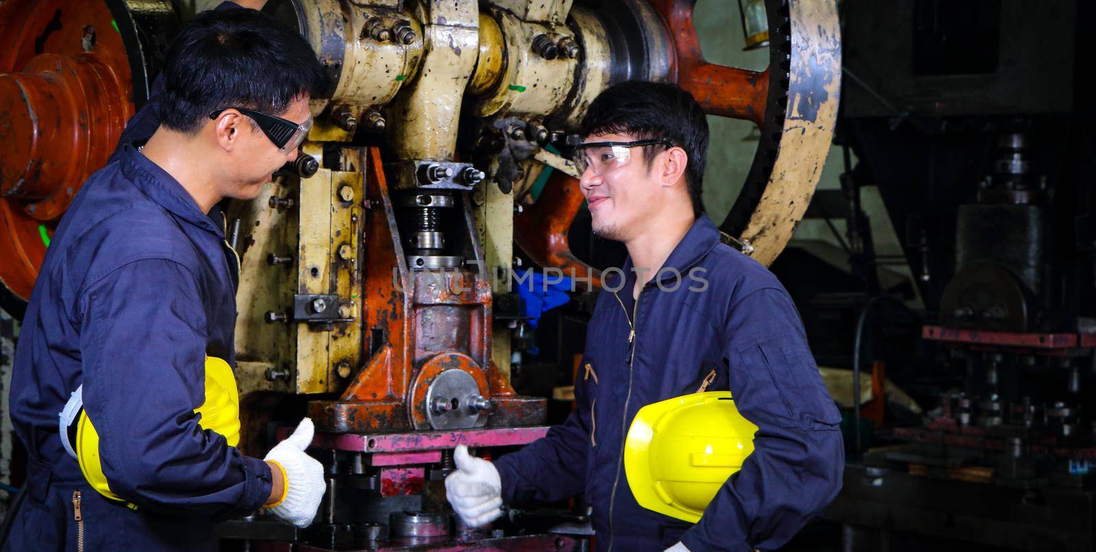 Two skilled Asian workers, dressed in helmet uniforms, are discussing machine repair analysis. by atitaph