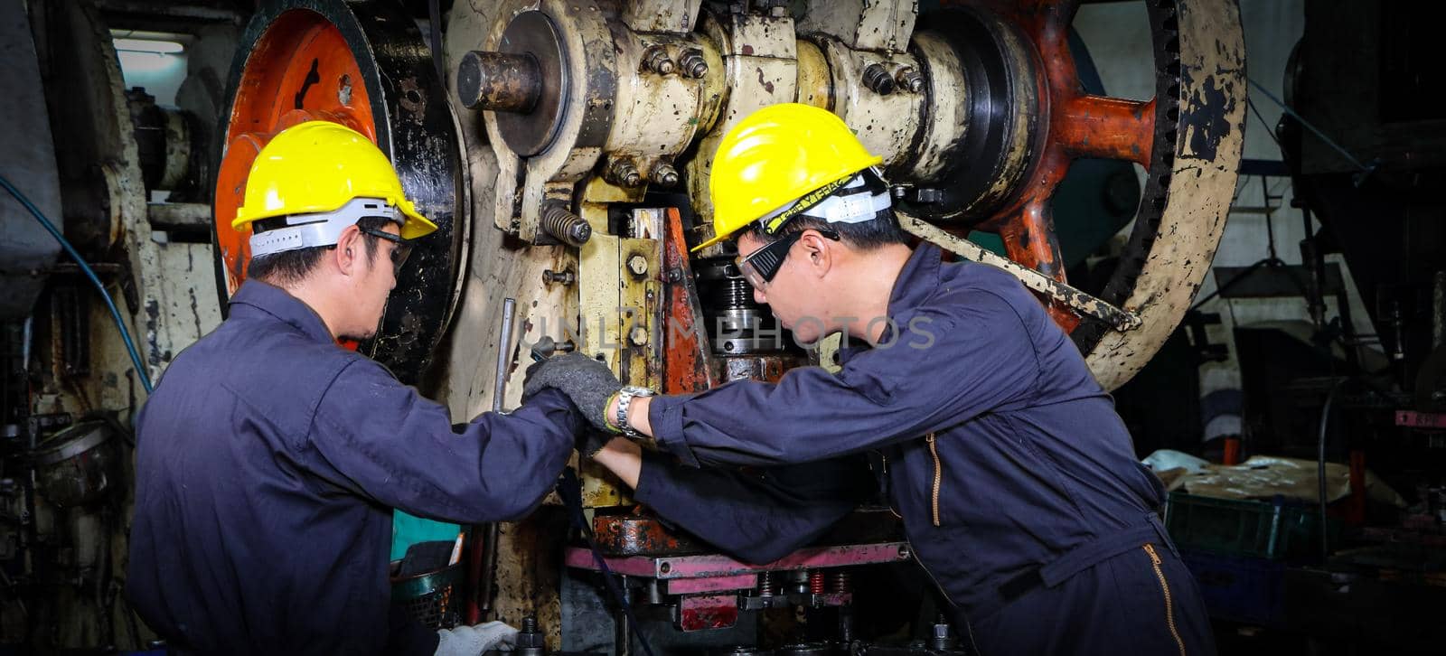 Asian male worker In industries that wear glasses, safety hats and safety uniforms Wrench tool holder stand Machine maintenance technician operation concept In an industrial factory with confidence