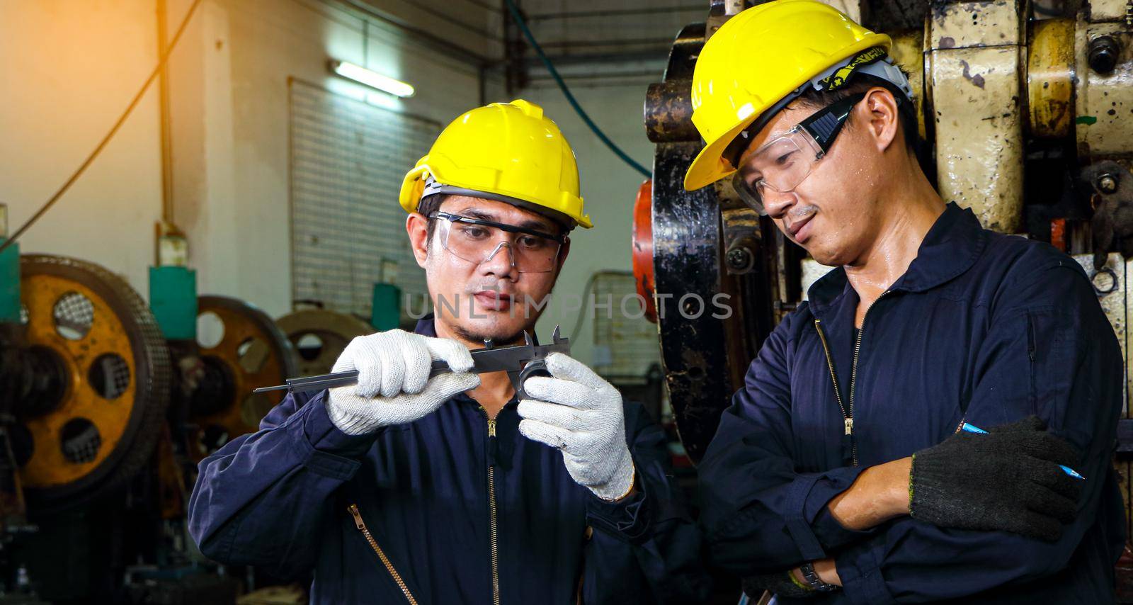 Asian engineer Safety uniforms use vernier calipers to measure workpieces. by atitaph