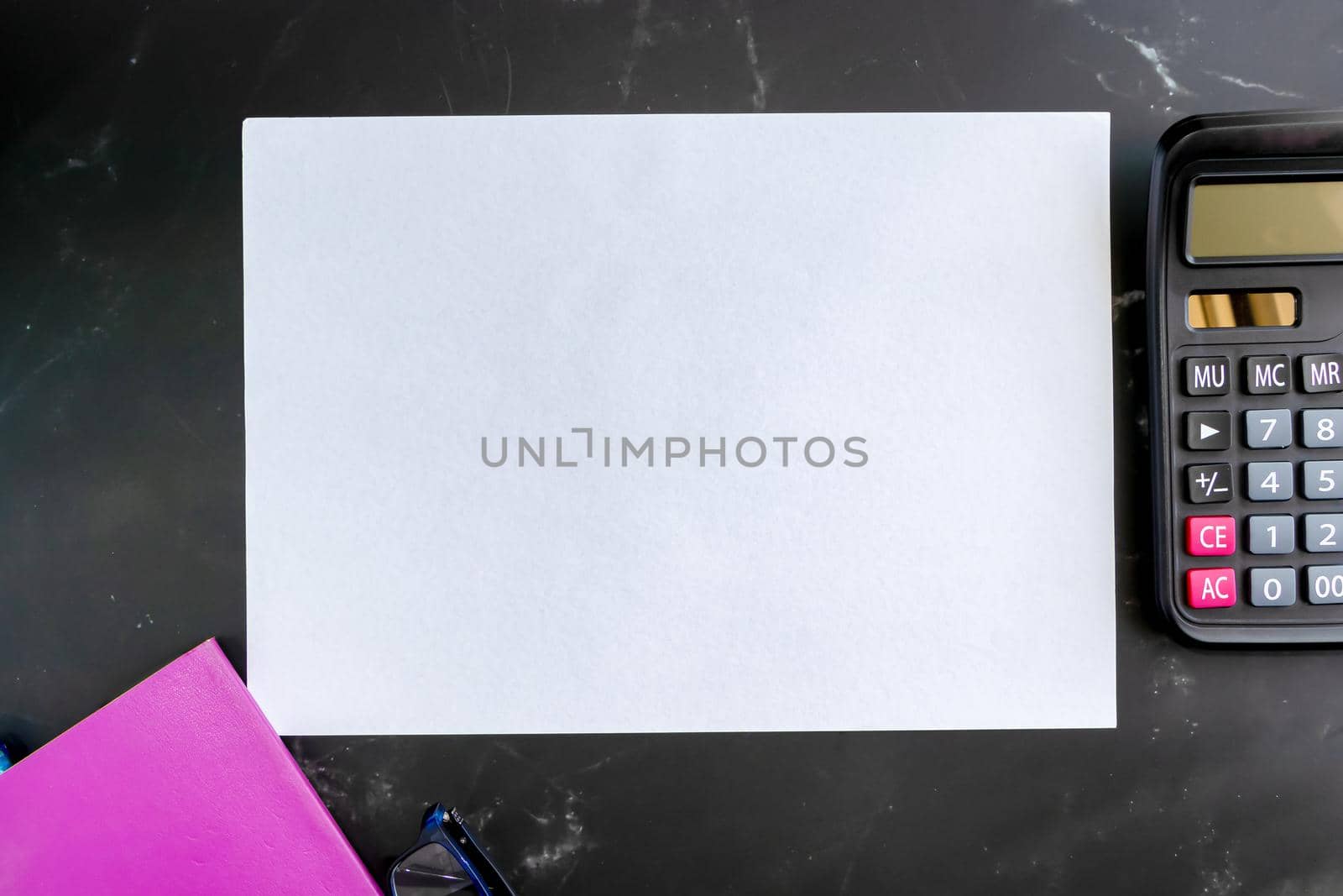 Top view Blank Notebook Calculator and glasses on a black marble table background. Simple financial business concepts, working at home or office for social distancing measures, plus copy space.