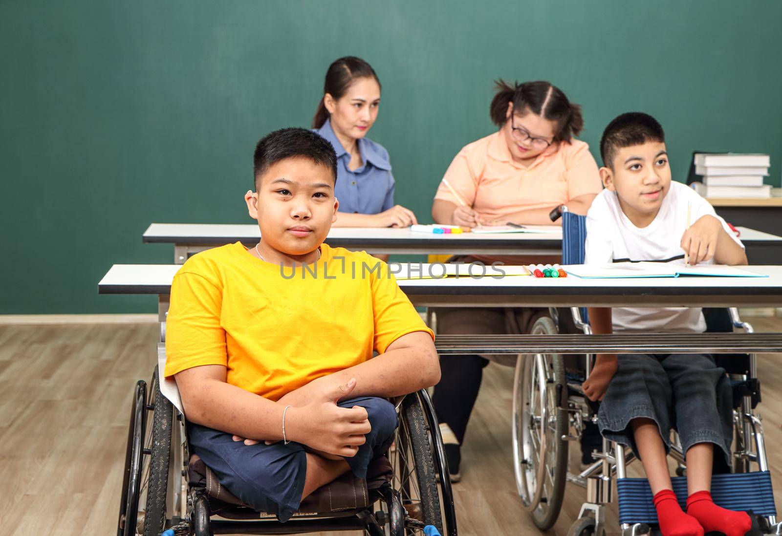 Asian disabled children Or, an autistic child learns to read, write, and train their hand and finger muscles with a teacher at their classroom desk. Concentrate and smile Happy disability kid concept