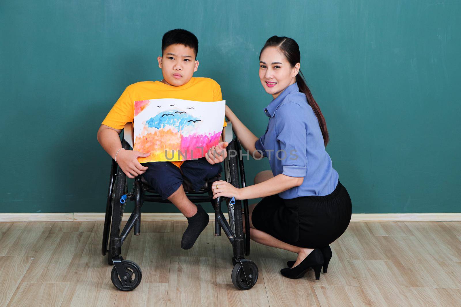 A group of young girls with disabilities and autism is training their hand and finger muscles by drawing and painting with water.  by atitaph