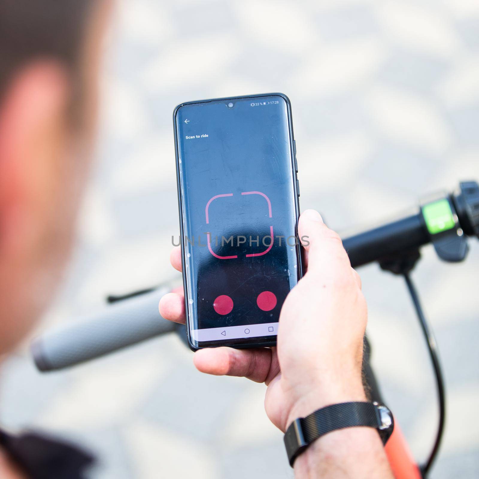 Close up of hand and smartphone, unlocking dockless electric scooter for rent with debranded generic phone app