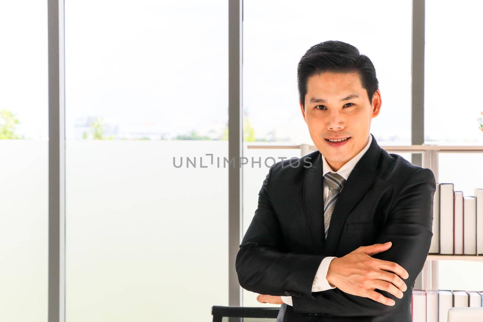 Portrait of an Asian adult businessman in a suit And stood looking at the camera, smiling happily He relaxed, confident and Are satisfied and diverse Work in the office Develop new business projects
