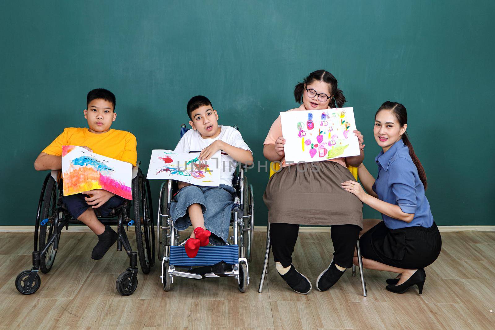 A group of young girls with disabilities and autism is training their hand and finger muscles by drawing and painting with water.  by atitaph