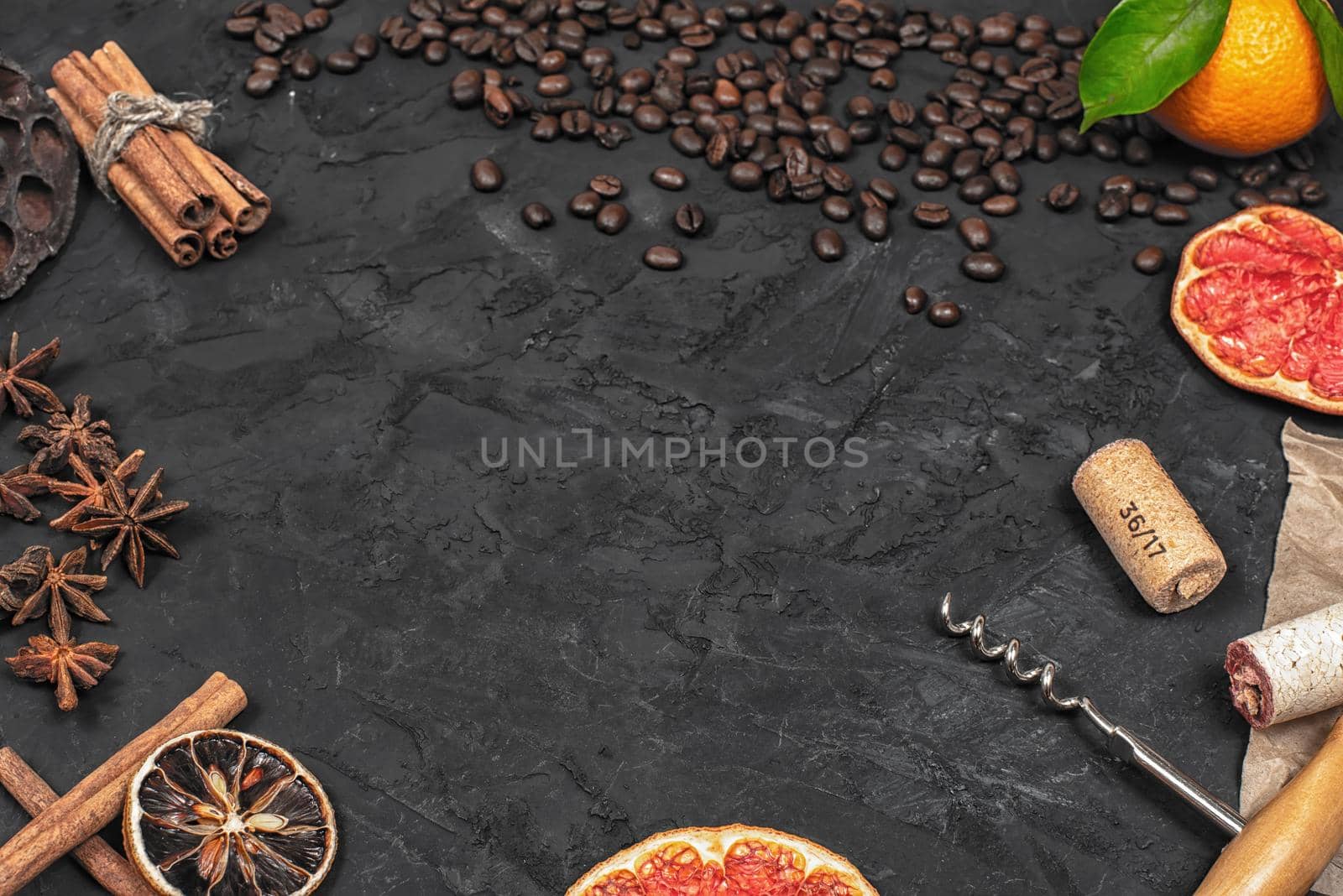 Flat lay photography of sticks of cinnamon knitted by twine, anise, coffee beans, corks and orange slice against a dark background