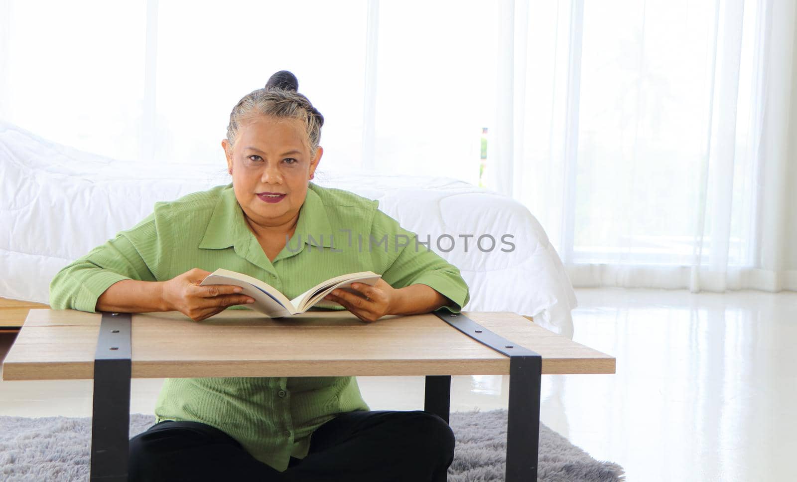 Senior Asian women Retirement Asians Sit and read movies and media at the wooden table in the bedroom. The concept of a relaxed retirement life Enjoy happy