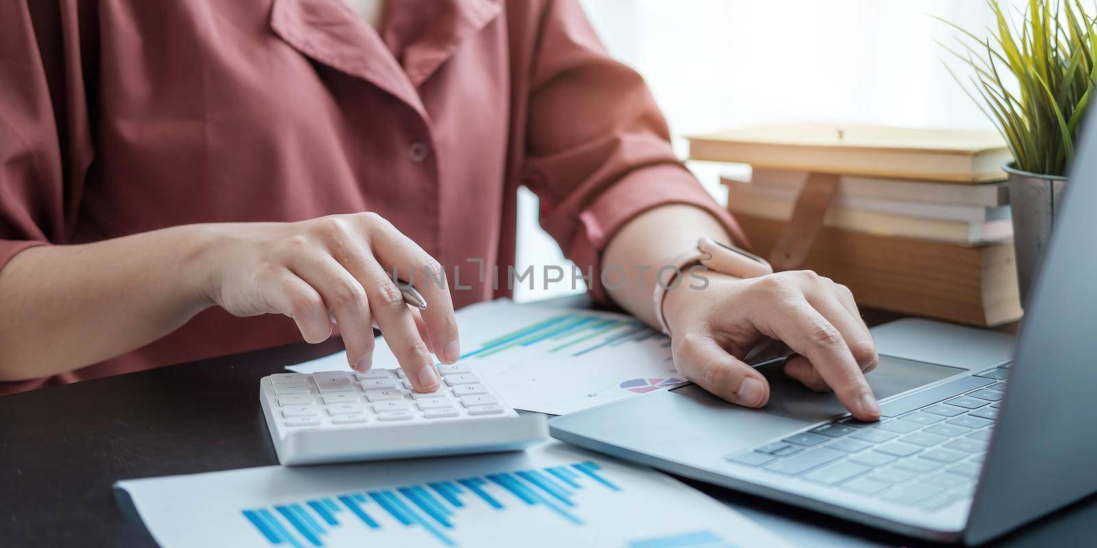 Woman with financial report and calculator. Woman using calculator to calculate report at the table in office by wichayada