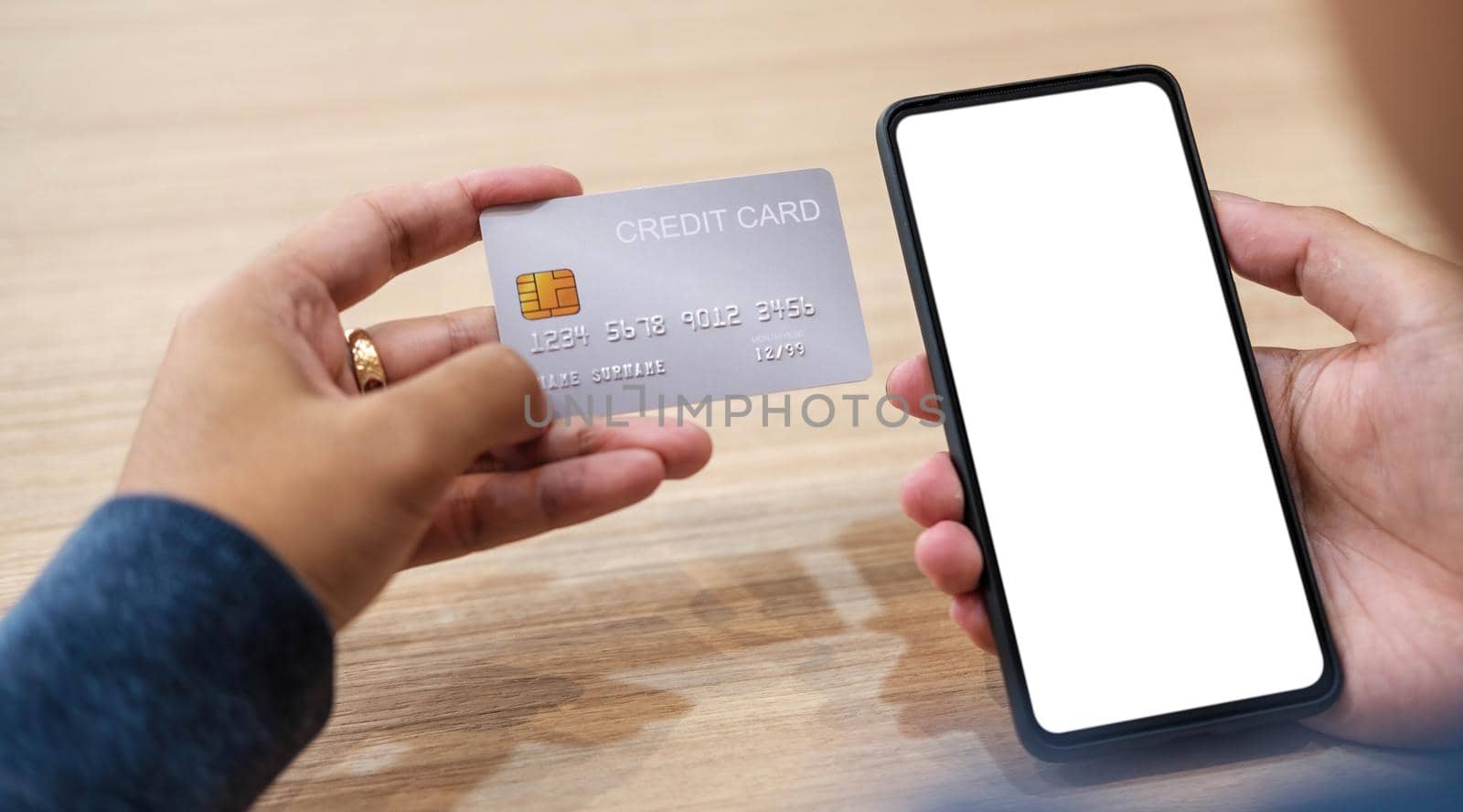 Close up hand of woman shopping online with credit card using smart phone at cafe by wichayada