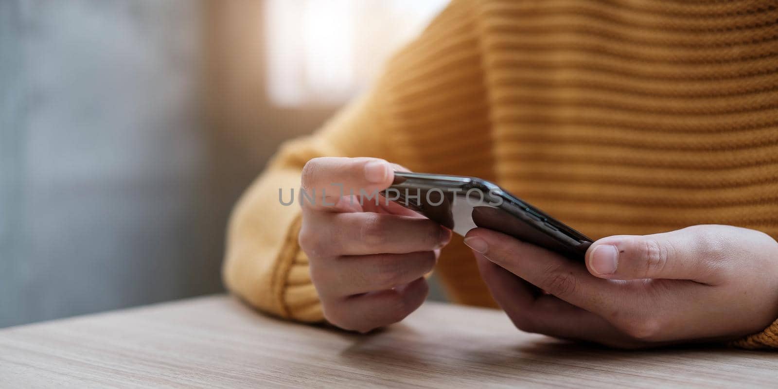 Closeup image of a woman holding and using mobile phone by wichayada