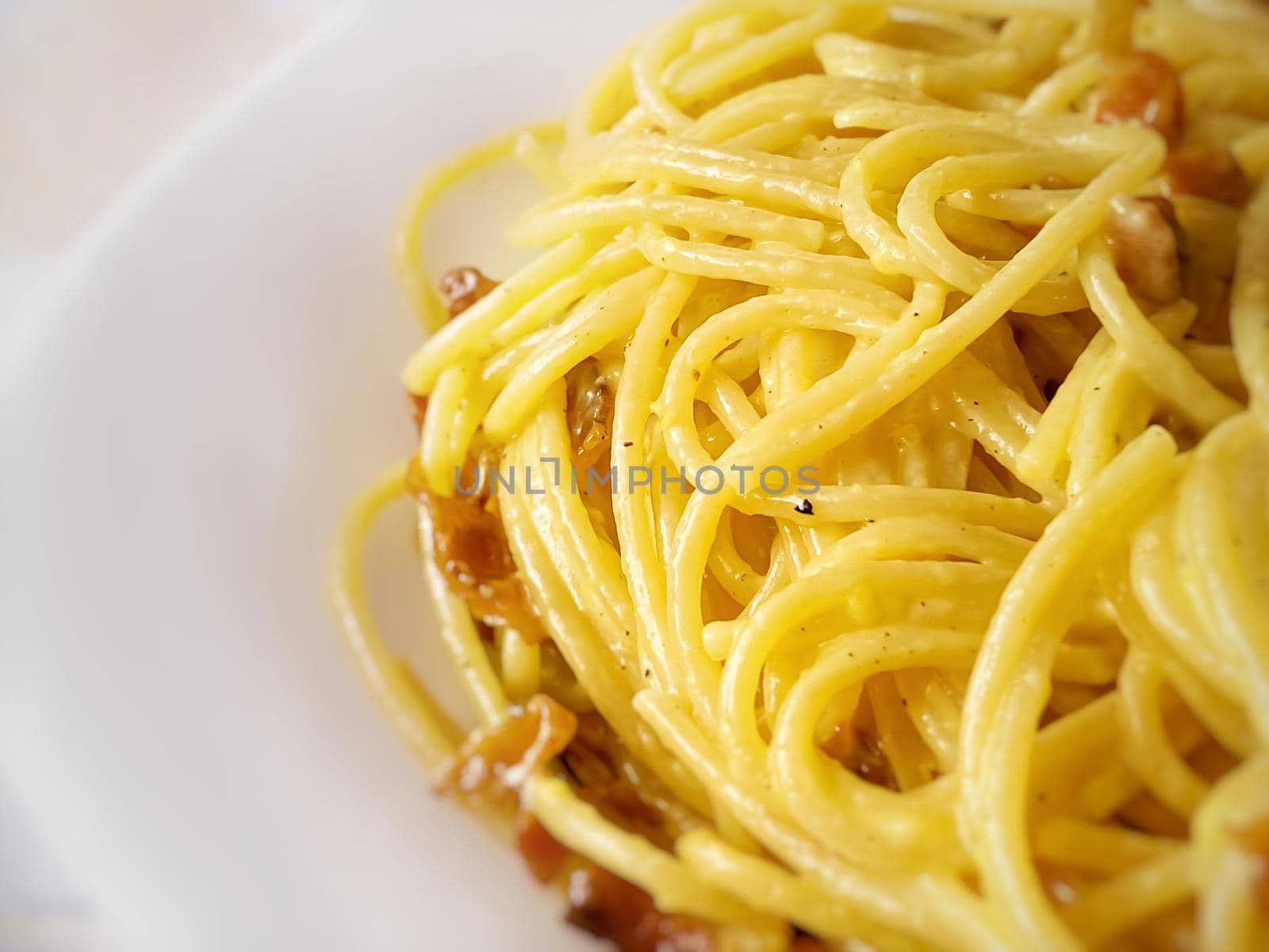 Close up of cooked spaghetti with carbonara sauce. Traditional recipe of Italian cuisine. Cooked pasta with yellow carbonara egg yolk sauce