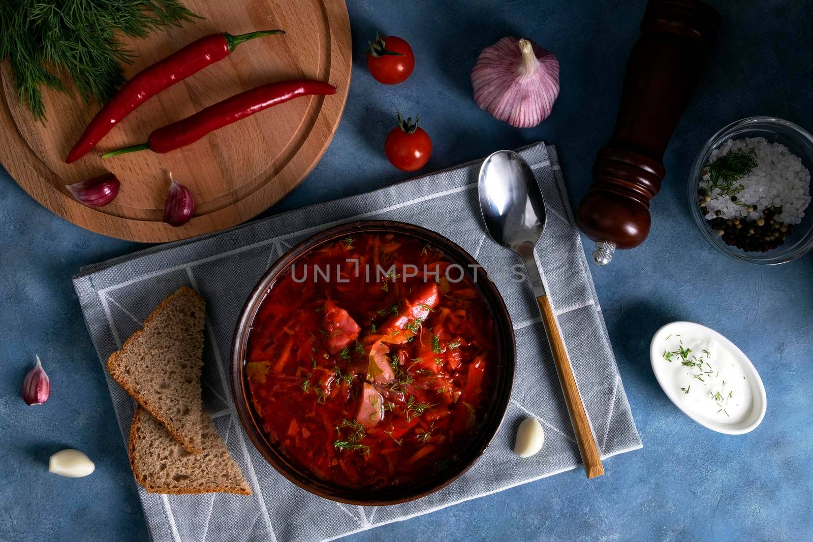 Top view of the traditional popular Russian soup borscht made from cabbage, beets and other vegetables served in a clay ceramic plate with sour cream and garlic. National cuisine. Selective focus.
