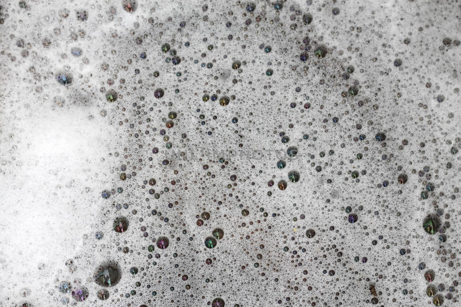 Detergent bubbles float in the waste water.