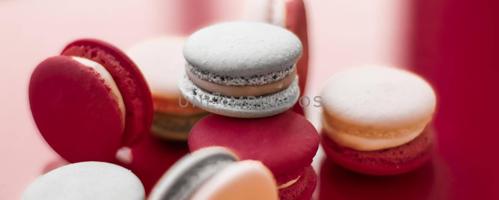 French macaroons on wine red background, parisian chic cafe dessert, sweet food and cake macaron for luxury confectionery brand, holiday backdrop design by Anneleven