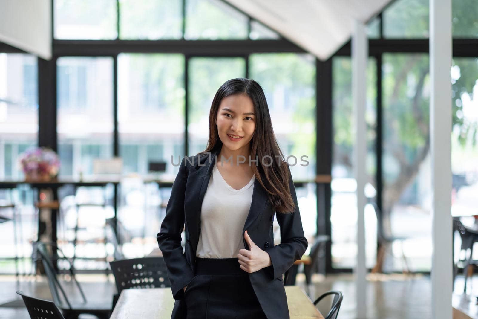 Portrait of successful young Asian businesswoman at office, She standing and looking at camera wears a black suit
