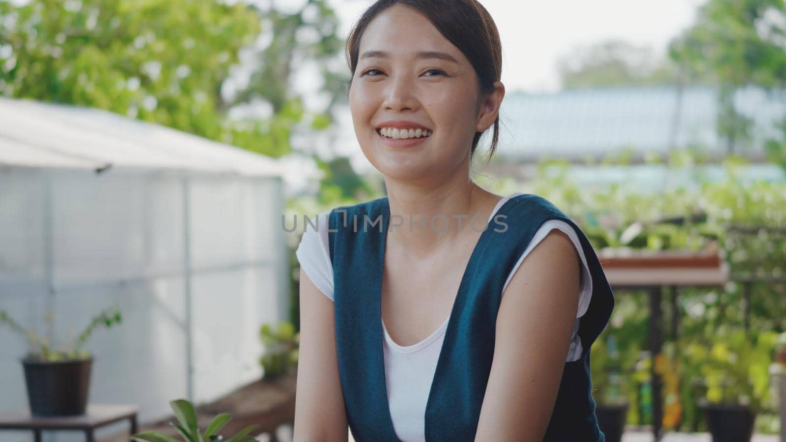 Positive beautiful young woman gardener smiling laughing looking to camera at greenhouse, Portrait of happy female confident smile