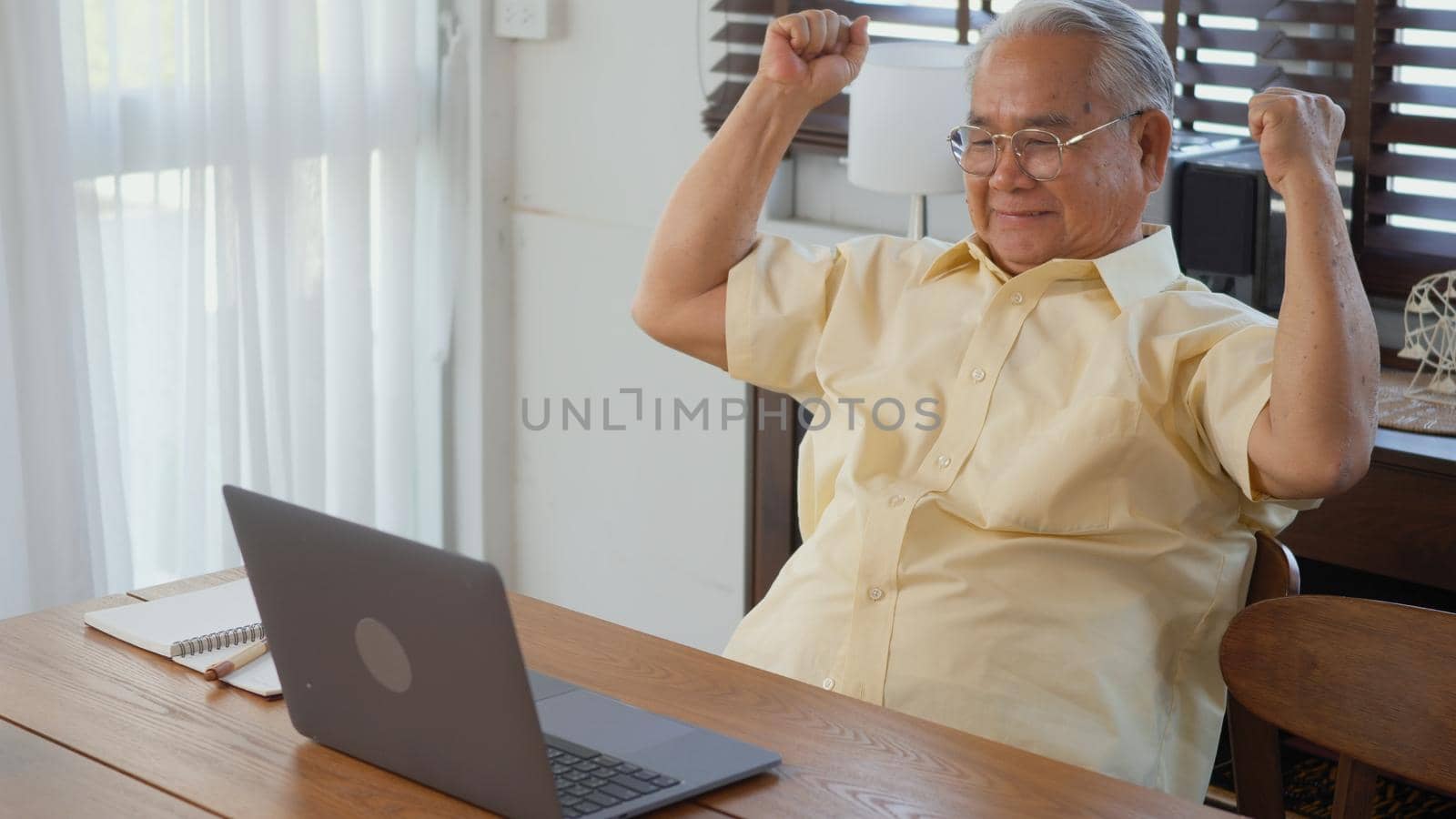 Senior man dressed wear eyeglasses sitting on chair working on laptop in living room at home, Happy old man retired using computer, Elderly grandfather work from home
